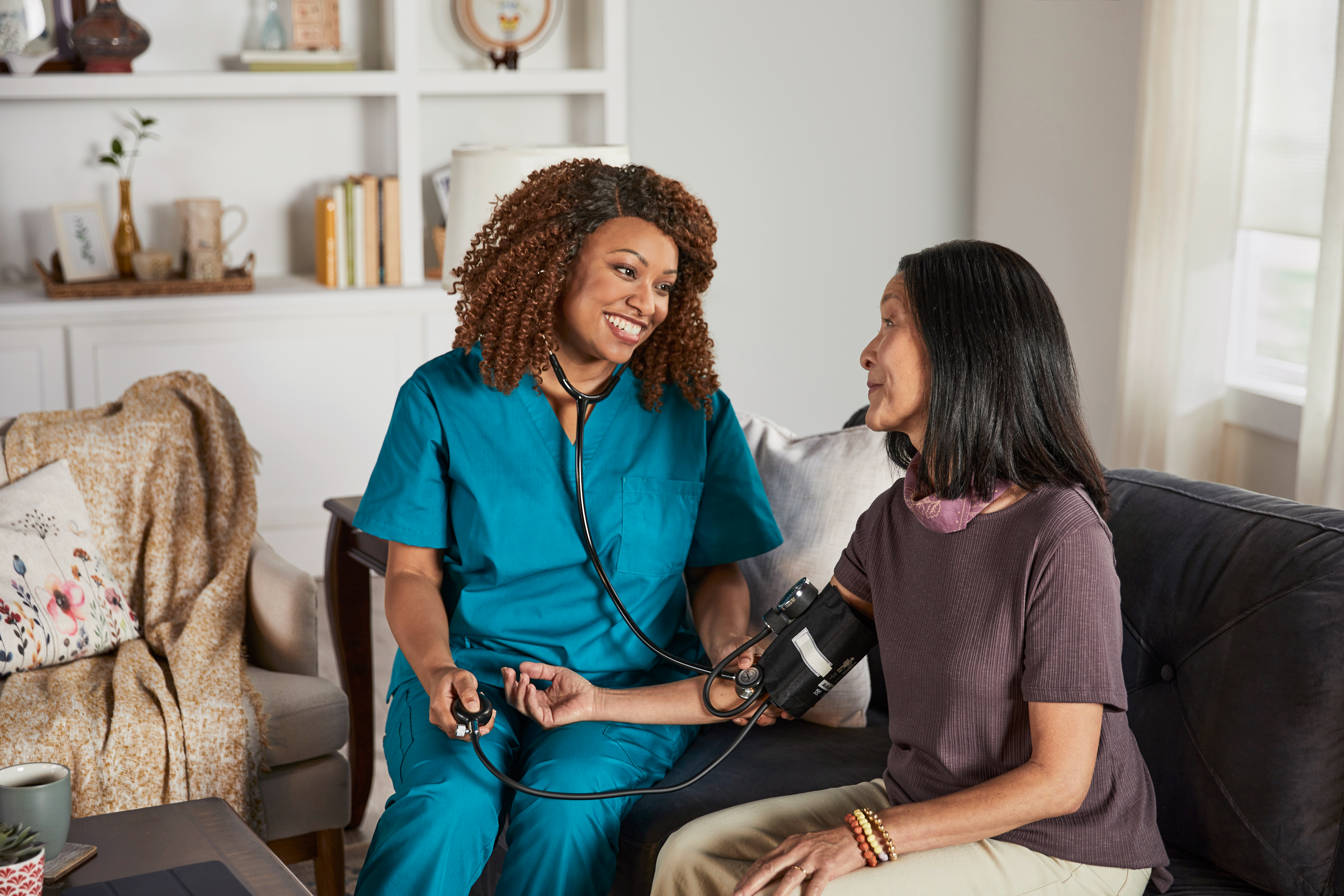 Nurse checking a women's blood pressure in her home